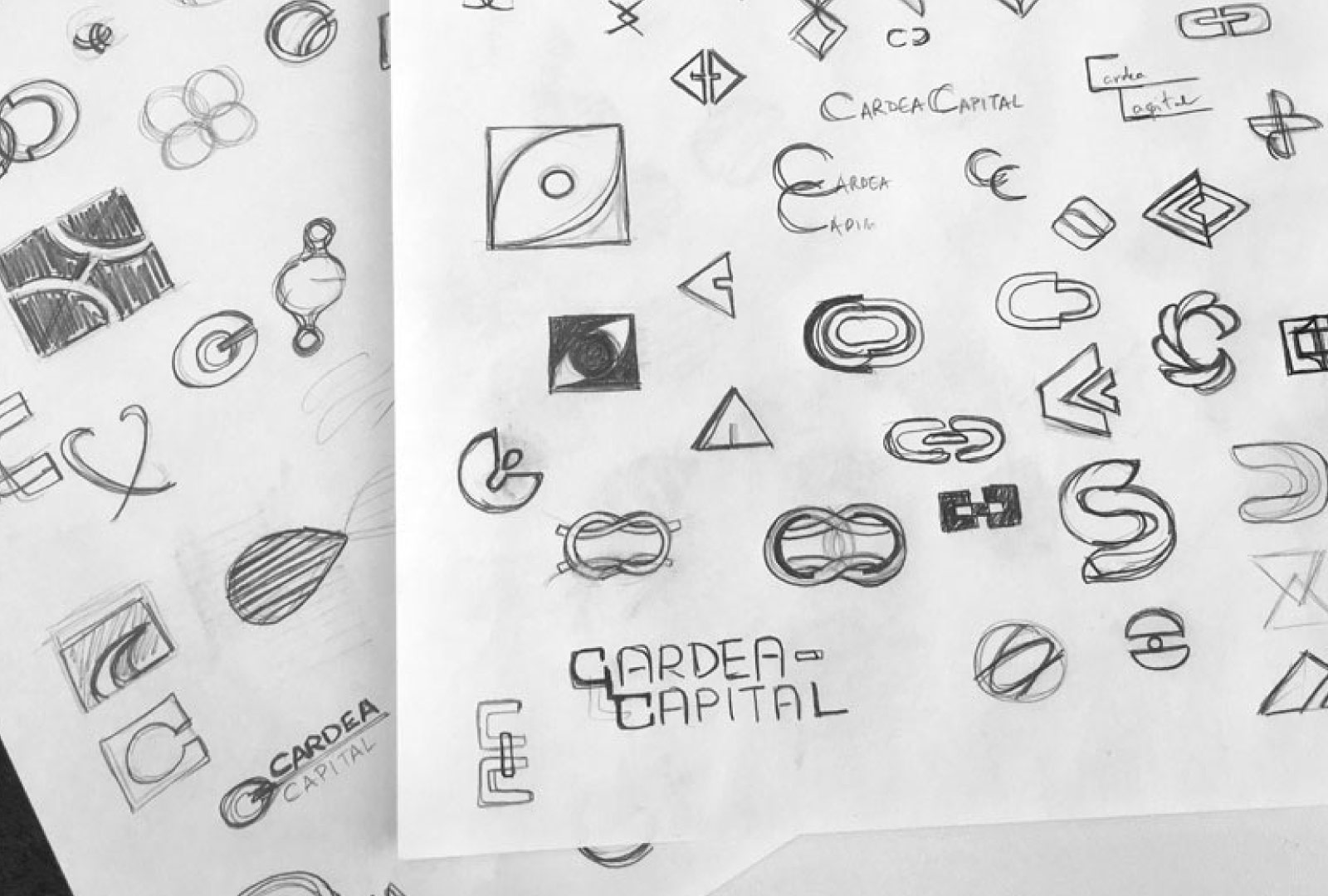 Two paper sheets full of sketches for the logo